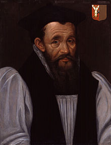 A head-and-shoulders portrait of Richard Bancroft. The portrait portrays Bancroft on a grey background, wearing a white shirt with a black vest. Bancroft is wearing a black cap and has collar-length brown hair. Over Bancroft's left shoulder is a red and brown family crest
