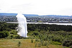 Vue du Strókur en éruption depuis le sommet du Perlan avec Kópavogur au second plan.