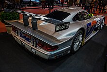 A silver CLK LM racecar is viewed from the rear three-quarter perspective, the car's wickerbill and fixed carbon-fibre wing are prominent features of the car.