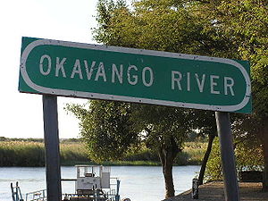 Uma placa do rio Ovakango, ou Cubango com uma balsa ao fundo.