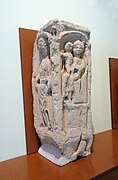 Pilastre en pierre sculptée représentant deux personnes et un enfant.