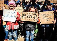 Gyerekek plakátokat tartanak, melyeken az szerepel: „Kenyeret és békét akarunk.” „UNICEF, hol vannak a gyerekjogok?”, „Mentsétek meg Fuát és Kafriját a biztos haláltól!”