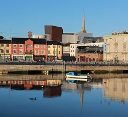 river estuary with houses on the quay and a church spire and modern opera house on the skyline