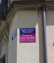 En dessous d'un panneau de rue bleu affichant "Boulevard des Philosophes", un second panneau violet affiche "Boulevard Marie-Huber,(1695-1753) Théologienne".