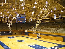 Interiér basketbalového stadionu s kurtem, krokvemi a prázdnými tribunami