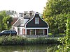 Houten molenaarshuis met klokgevel (uit- en ingezwenkt voorschot) uit 19e eeuw, ernaast molen d' Armiraal