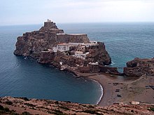 A small fortification built on a rocky islet with a sandy connection to the mainland