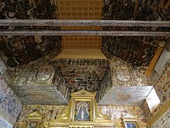 Pintura de Santa Ana en el techo del presbiterio. A los lados, escudos de Felipe IV y las representaciones del sol naciente y poniente