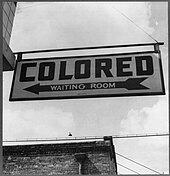 "Colored" waiting room sign in 1943 for a bus terminal in Rome, Georgia, where Jim Crow laws created "de jure" legally required segregation Sign at bus terminal in Rome, Georgia.jpg