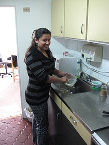 A Colombian domestic worker. Neighborhood friends and family sharing household and childcare responsibilities is an example of non-market activity performed outside of the traditional labor market. Trabajadora domestico.JPG