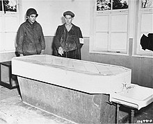 Un soldat américain et un FFI examinent la table d'autopsie dans le block crématoire. 1944.