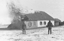 Два Ваффен-СС смотрят на горящий фермерский дом под Харьковом, февраль 1943 г.
