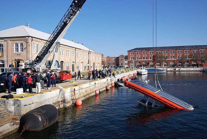 A crane capsizes a small coast guard vessel to test its righting ability