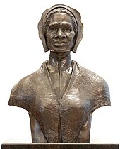 Buste en bronze d'une femme noire d'âge mur portant un bonnet, un chemisier à col montant et un châle