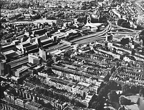 Montage photographique en noir et blanc d'une autoroute bordée d'immeubles modernes au cœur d'une ville dense.