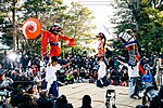 Men with large Chinese lion shaped dolls on their shoulders.