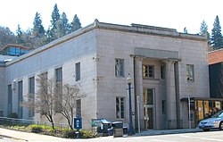 Photograph of a large building on a city street corner with the front entry flanked by two tall pillars