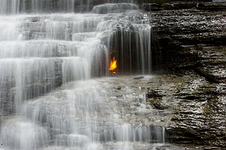 Die "ewige Flamme" 2009 hinter dem Wasserfall
