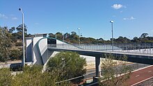 A footbridge across a freeway connecting to a train station