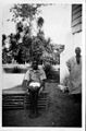 "Boy" Selu sitting on a chair made by the carpenter to the right, Panguma, Sierra Leone, 1934