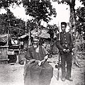 Image 31Temne leader Bai Bureh seen here in 1898 after his surrender, sitting relaxed in his traditional dress with a handkerchief in his hands, while a Sierra Leonean West African Frontier Force soldier stands guard next to him (from Sierra Leone)