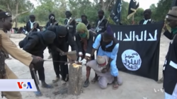 Boko Haram fighters cutting the hand of a man in 2017 Boko Haram Execution.png