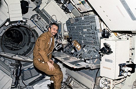 O Garriott est installé au pupitre de commandes des télescopes dans le module MDA.