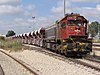 An Israel Railways EMD G26 locomotive pulling a ballast train south of Lod station in 2006