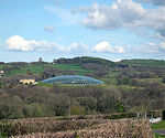 a large glass structure within a landscape of trees and hills