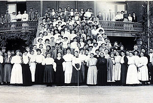 Black and white portrait of a large group of women students posing on a staircase.