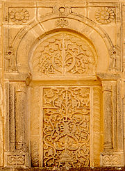 Photographie d’un panneau sculpté de la façade du portique occidental de la cour.