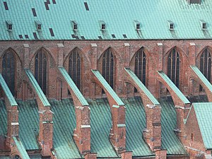 Arching above a side aisle roof, flying buttresses support the main vault of St. Mary's Church, in Lubeck, Germany. Lubeck Marienkirche Strebebogen.jpg