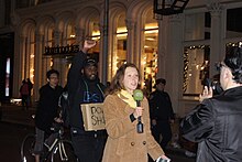 A protester photobombing a news reporter during a protest in New York City NYC Mike Brown-Ferguson protest Broadway 3.JPG