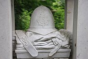 Photographie en couleurs d'une sculpture en pierre représentant un casque de police au-dessus d'un uniforme plié.