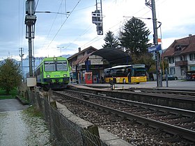 de Bahnhof Tuurne mit eme Zug vor BLS und eme Poschtouto