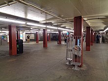 The mezzanine of the 47th–50th Streets–Rockefeller Center station. There are several passengers walking toward a turnstile in the background.