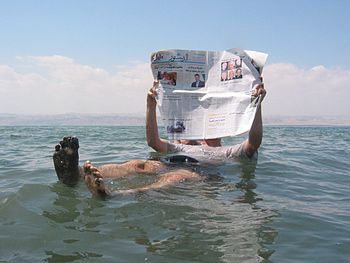 Čovek čita novine u Mrtvom moru.