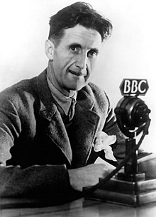 Photograph of George Orwell sitting in front of a microphone