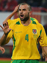 A man wearing a yellow and green football shirt during a game.