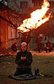 Чеченець молиться протягом Битви за Грозний (1994—1995). На задньому плані горить газ з пошкодженого шрапнеллю газопроводу, січень 1995 р.