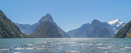 L'eau de l'océan au premier plan, et au fond des montagnes très découpées.