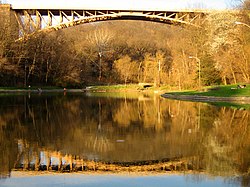 A picture of the lake with the Panther Hollow Bridge rising above it