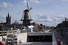 Photographie en couleurs d'un moulin à vent entouré d'un paysage urbain en travaux.