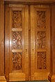 Дверь в комнату раритета, вырезанная по проекту Эрика Гилла в 1935 году. На каждой панели изображен известный ученый.