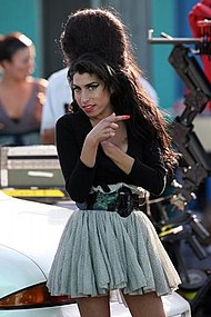 Knee high portrait of woman in her twenties wearing a short gathered skirt, light gray dress and dark cardigan