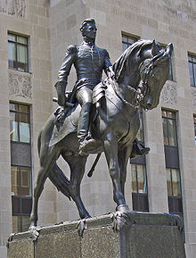 Statue of a man on a horse in front of a large stone building