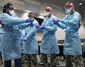 Florida National Guard soldiers collaborate with hospital staff to don personal protective equipment