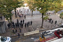 Des opposants à la rénovation de la place Jean-Jaurès de Marseille manifestent pacifiquement devant un groupe de CRS, pendant qu'un muret de béton est installé.