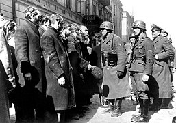 Photo from Nowolipie Street. In the back (from the left) are townhouses at Nowolipie 32 (fragment), 30 and 28.[18] center is Heinrich Klaustermeyer; right Josef Blösche. Similar picture, Stroop Report original caption: "Jewish Rabbis."