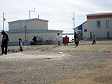 Women carry their children in amautiit while walking to Northern Store, past Isuma productions (left) and the Coop hotel (right)